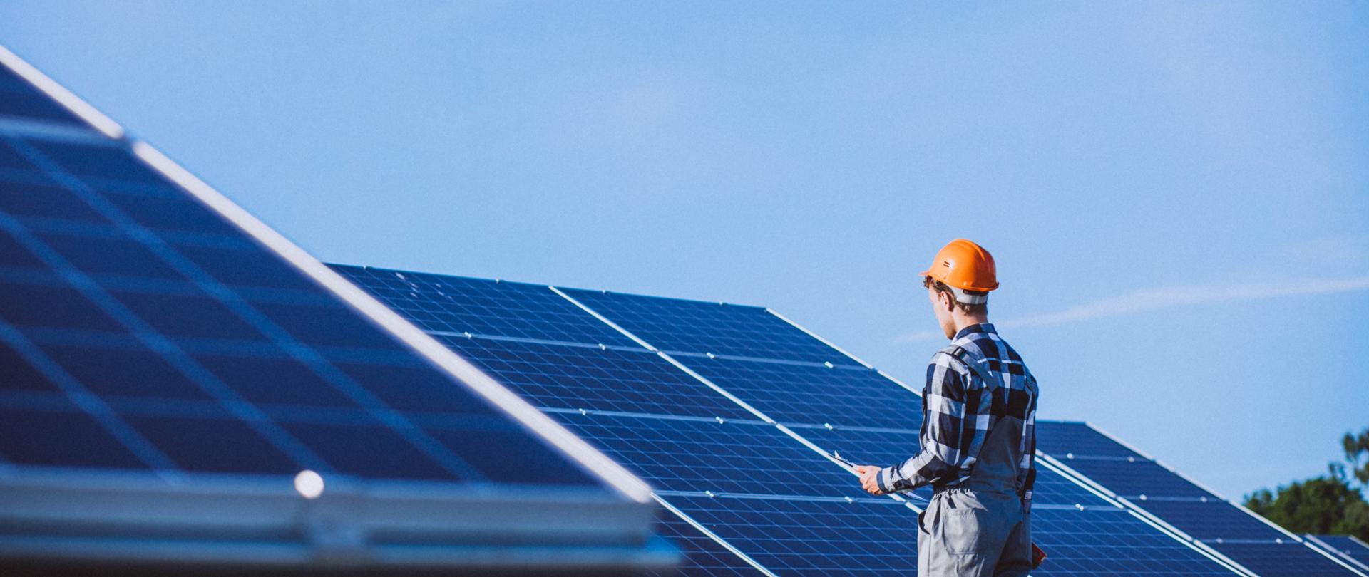 Man worker in the firld by the solar panels