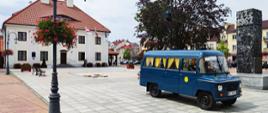 Zabytkowa niebieska nyska oznaczona logiem PKS stoi na płycie rynku miejskiego w Przasnyszu. Po prawej obelisk autorstwa Edmunda Majkowskiego a w tle Muzeum Historyczne w Przasnyszu.