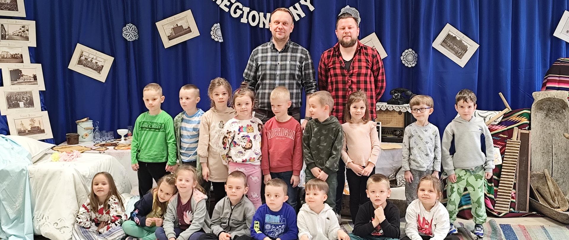 2 mężczyzn i grupa dzieci na tle napisu kącik regionalny