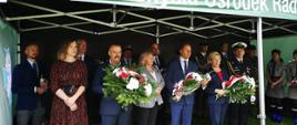 Zdjęcie wykonano w Parku Miejskim przy ulicy Makowskiej w Przasnyszu. Na fotografii przedstawiciele delegacji przybyłych na przasnyskie obchody wybuchu II Wojny Światowej. Od lewej Wiceburmistrz Przasnysza Łukasz Machałowski, Przewodnicząca Rady Powiatu Przasnyskiego Katarzyna Wróblewska, Sekretarz Przasnysza Jarosław Szmulski, Wicestarosta Przasnyski Waldemar Trochimiuk, Sekretarz Gminy Przasnysz Bożena Rudzińska, Dyrektor Zespołu Szkół Powiatowych w Przasnyszu Paweł Szczepkowski, Wiceprzewodniczący Rady Gminy Przasnysz Robert Kacprzak, Poseł Anna Cicholska. W tle przedstawiciele służb mundurowych oraz Burmistrz Przasnysza Łukasz Chrostowski.