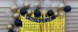  Złote paski a na nich balony oraz napis ANDRZEJKI.