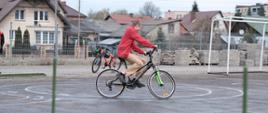 Uczeń na rowerze wykonuje ćwiczenia praktyczne