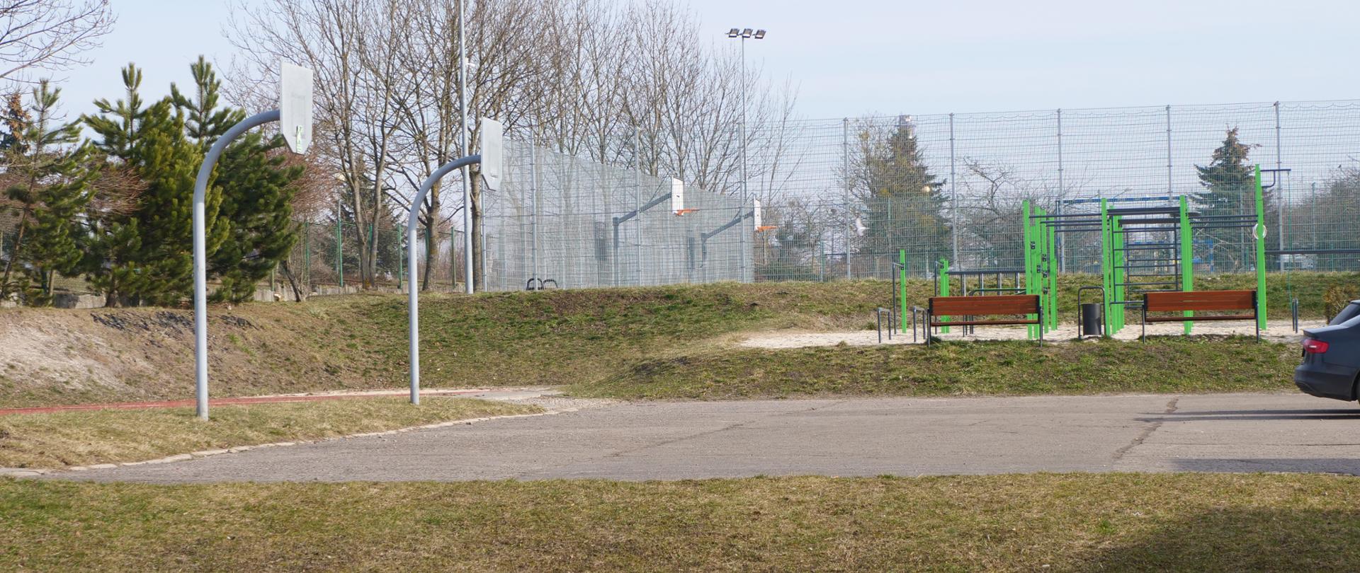 Zdjęcie przedstawia betonowe boisko, na którym stoją dwa kosze do koszykówki