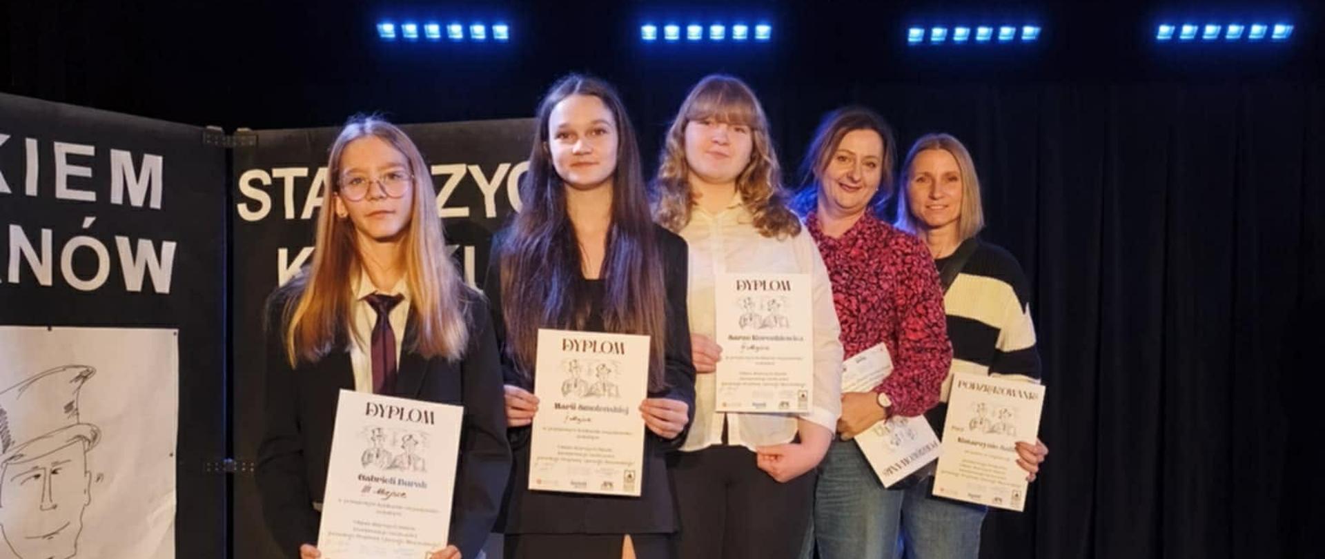 Trzy uczennice, które występowały w konkursie pozują wraz z dwiema Paniami, które je przygotowywały do wspólnego zdjęcia. Wszyscy trzymają w dłoniach dyplomy