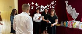 Uczeń klasy 8 idzie do żegnających go uczniów klasy 7 po czerwonym dywanie