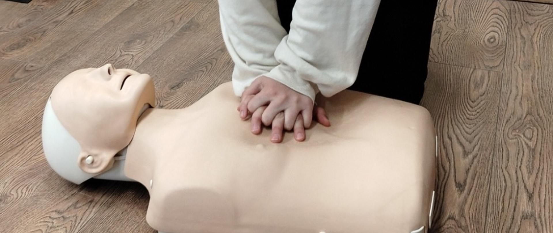 Uczennica wykonuje masaż serca na manekinie