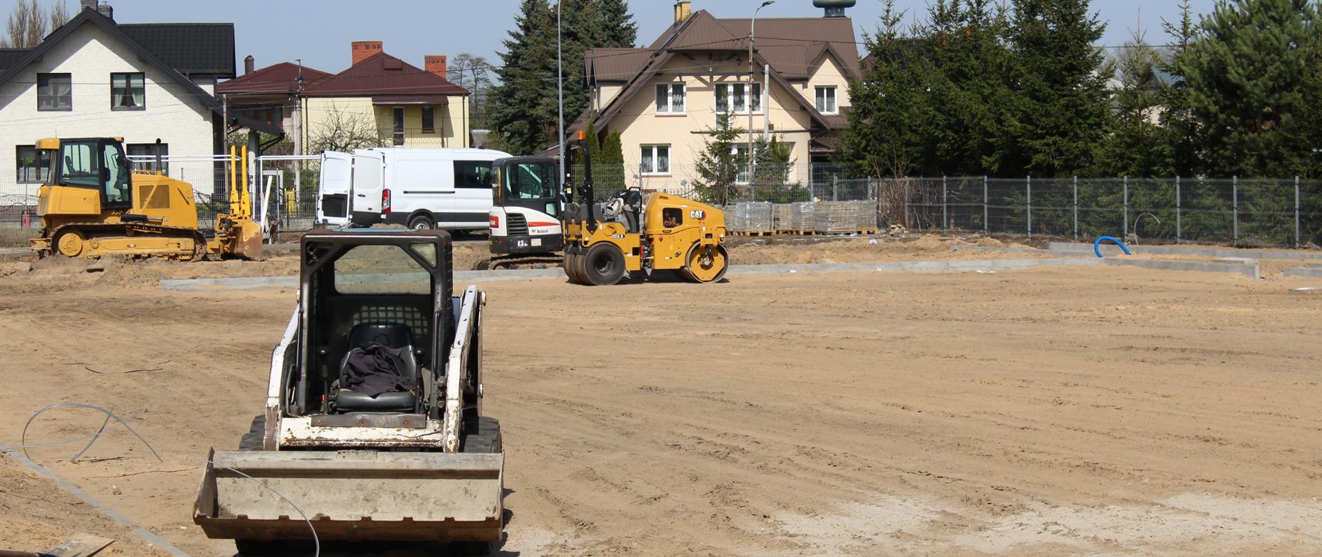 Plac budowy - maszyny budowlane stoją na piaszczystej powierzchni - przyszłym boisku