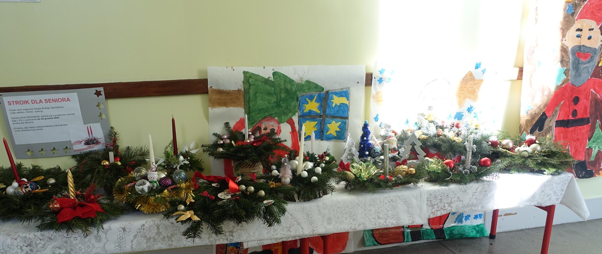 Stroiki wyeksponowane na stolikach stojących na korytarzu szkolnym.