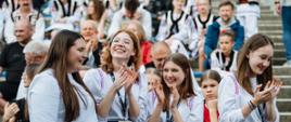 Uczennice z zespołu wokalnego z uśmiechem obserwują występy kolegów