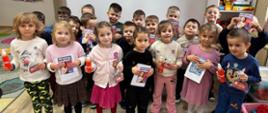 Grupa dzieci pokazuje granty otrzymane w ramach programu "Przedszkola bez owsików"