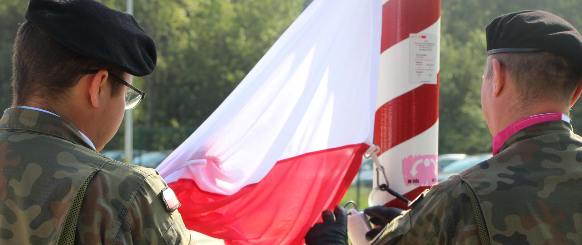na zdjęciu znajdują się żołnierze 2.BPL, którzy trzymają Polską flagę
