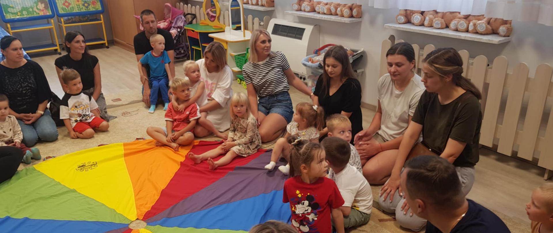 Rodzice z dziećmi na dywanie podczas zabawy