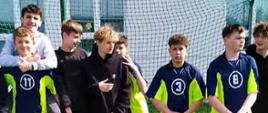 Zawodnicy z klas 7-8 w granatowo-zielonych strojach stoją w bramce piłkarskiej