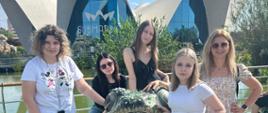 Uczennice pozują do zdjęcia przy rzeźbie żaby