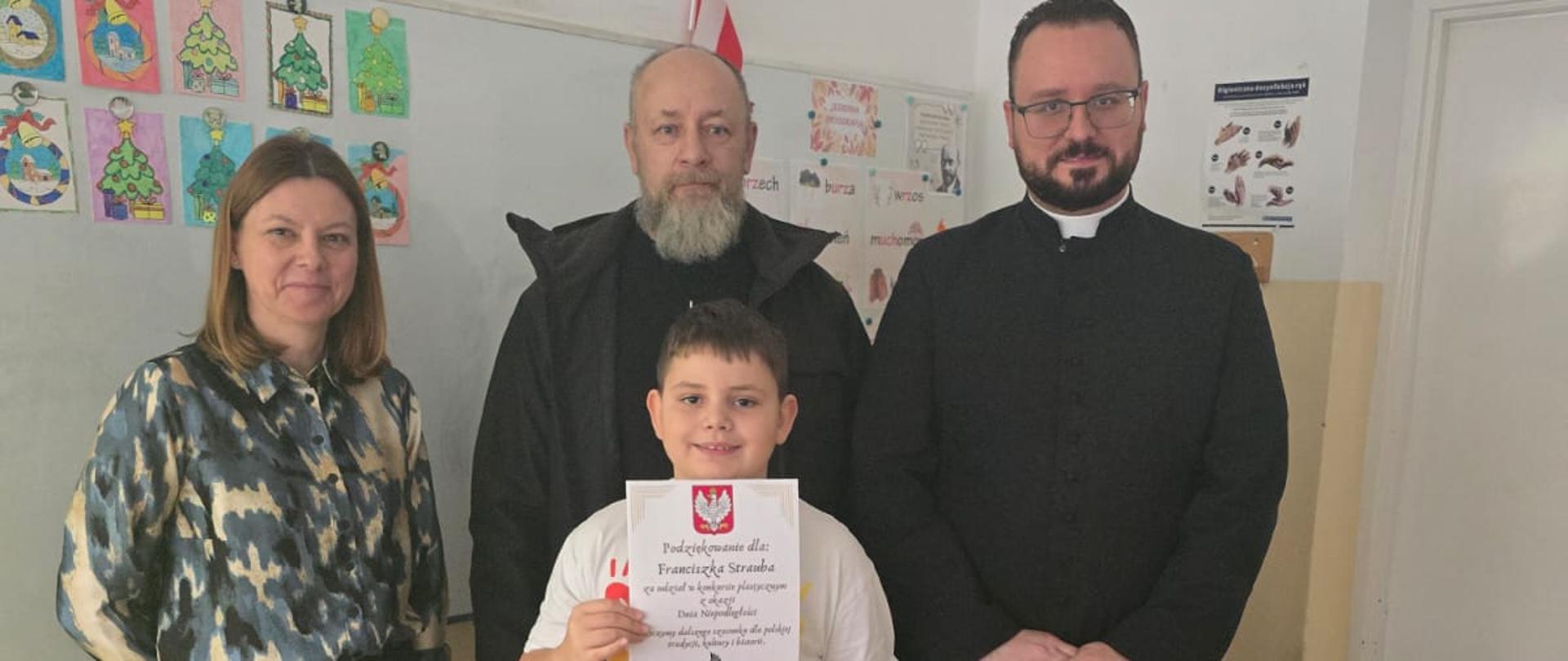 Wyróżniony uczeń z panią dyrektor, przedstawicielem fundacji oraz księdzem
