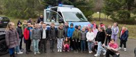 Dzieci z klas 1-3 stoją przed policyjną furgonetką