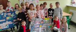 Uczniowie stoją w grupie, trzymają w ręku 2 plakaty wykonane w ramach projektu