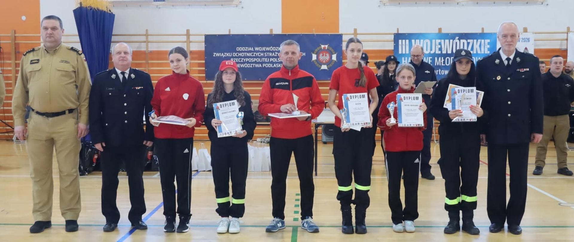grupowe zdjęcie z nagrodzonymi uczestnikami III Wojewódzkich Halowych Młodzieżowych Zawodów Sportowo-Pożarniczych, w których udział wzięły drużyny z całego województwa podlaskiego.
​