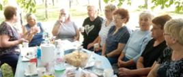 seniorki siedzą przy stole zastawionym napojami i jedzeniem 