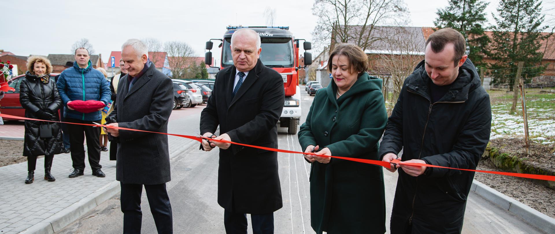 grupa ludzi przecinających czerwoną wstęgę