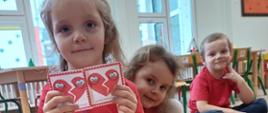 Dzieci siedzą na dywanie, mają przed sobą karty - będące częścią gry edukacyjnej