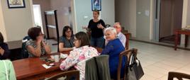 Podczas warsztatów kulinarnych - uczestnicy siedzą przy stole, słuchają trenerki