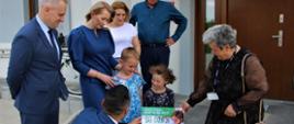 Kobieta wręcza czek na kwotę 90 tysięcy złotych dla powiatu polkowickiego na ręce dzieci. Są obecne władze powiatu polkowickiego.