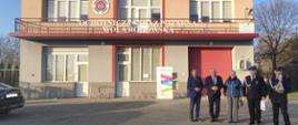 Budynek Ochotniczej Straży Pożarnej w Woli Radłowskiej z grupą osób stojących przed wejściem