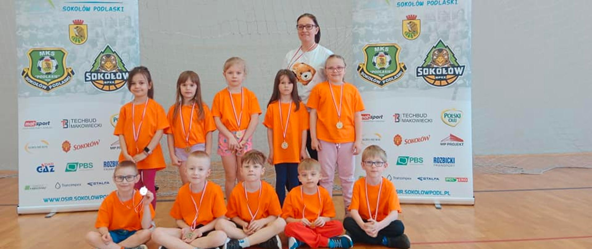 Nauczycielka i 10dzieci w pomarańczowych koszulkach