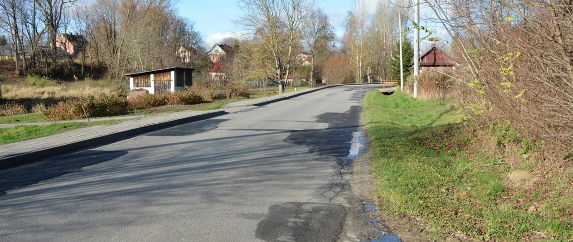 zdjęcie jezdni i chodnika przed remontem w tle drzewa i ogrodzenie, jesienna aura 
