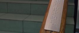 nakładka z informacjami w alfabecie braille'a , zamontowana na poręczy