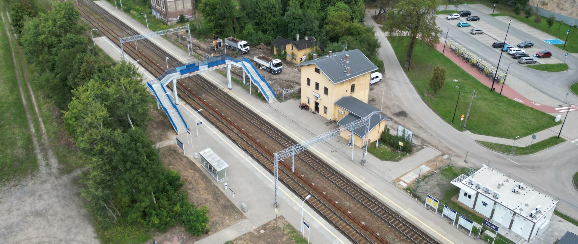 Widok z lotu ptaka na stację kolejową z żółtym budynkiem.
