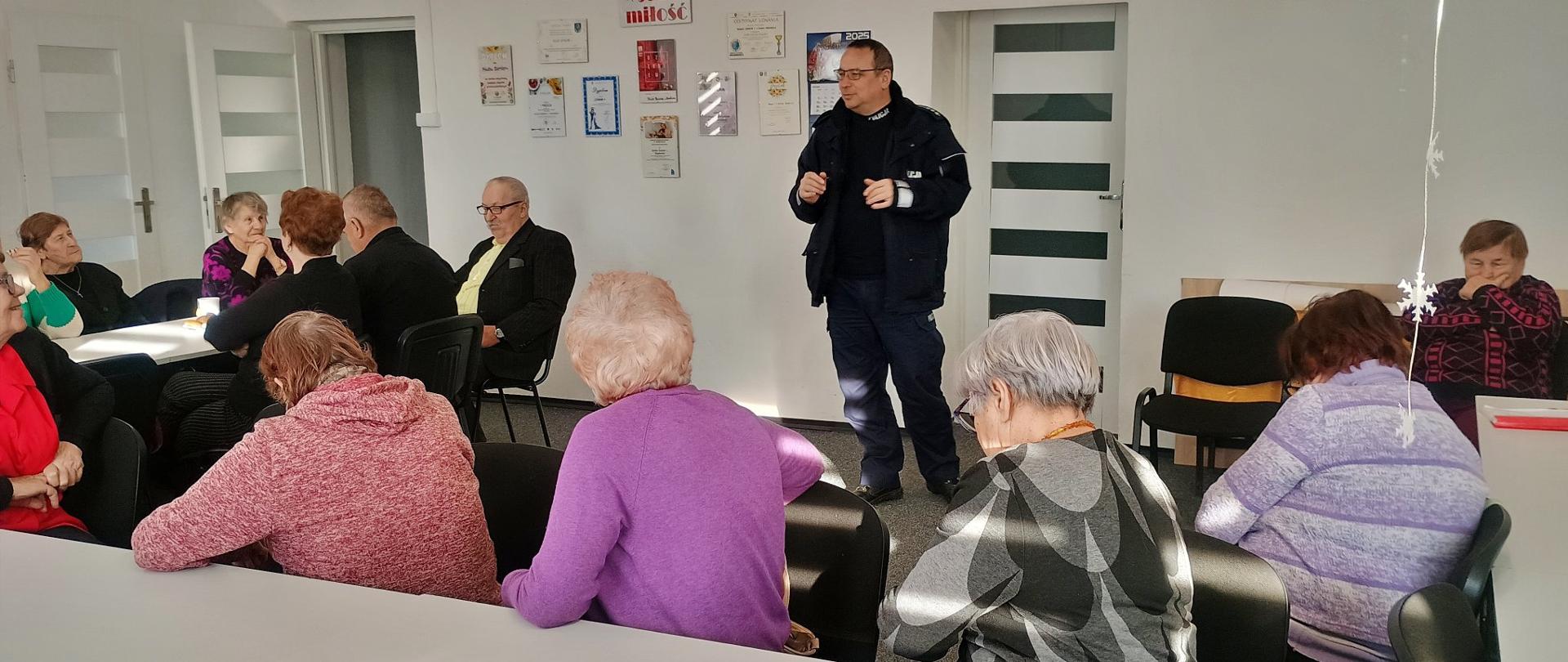 Seniorzy wysłuchują prelekcji związanych z bezpieczeństwem prowadzonych przez policjanta