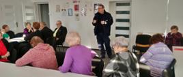Seniorzy wysłuchują prelekcji związanych z bezpieczeństwem prowadzonych przez policjanta