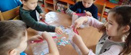 Dzieci w trakcie warsztatów - dzieci siedzą przy stole, grupują wycinanki