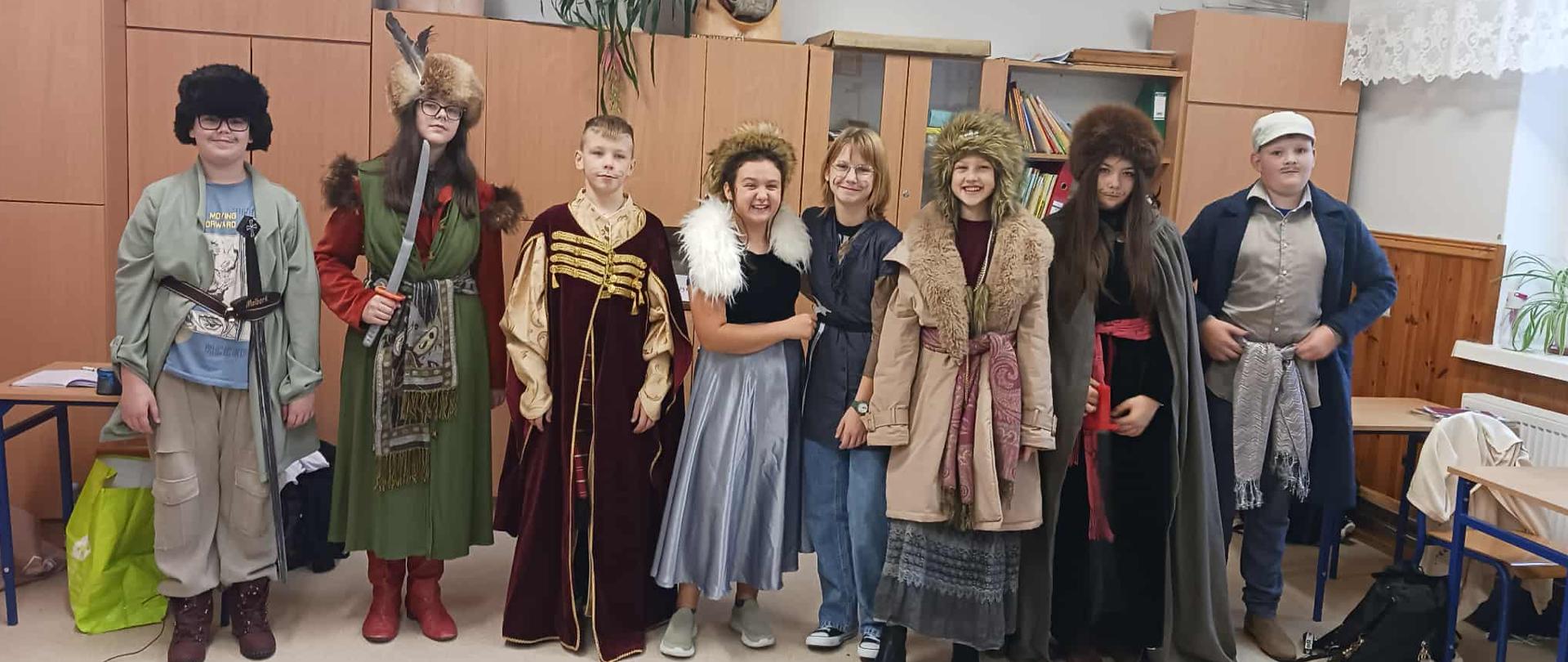 Ośmioro uczniów ubranych w dawne stroje szlacheckie pozuje do wspólnego zdjęcia.