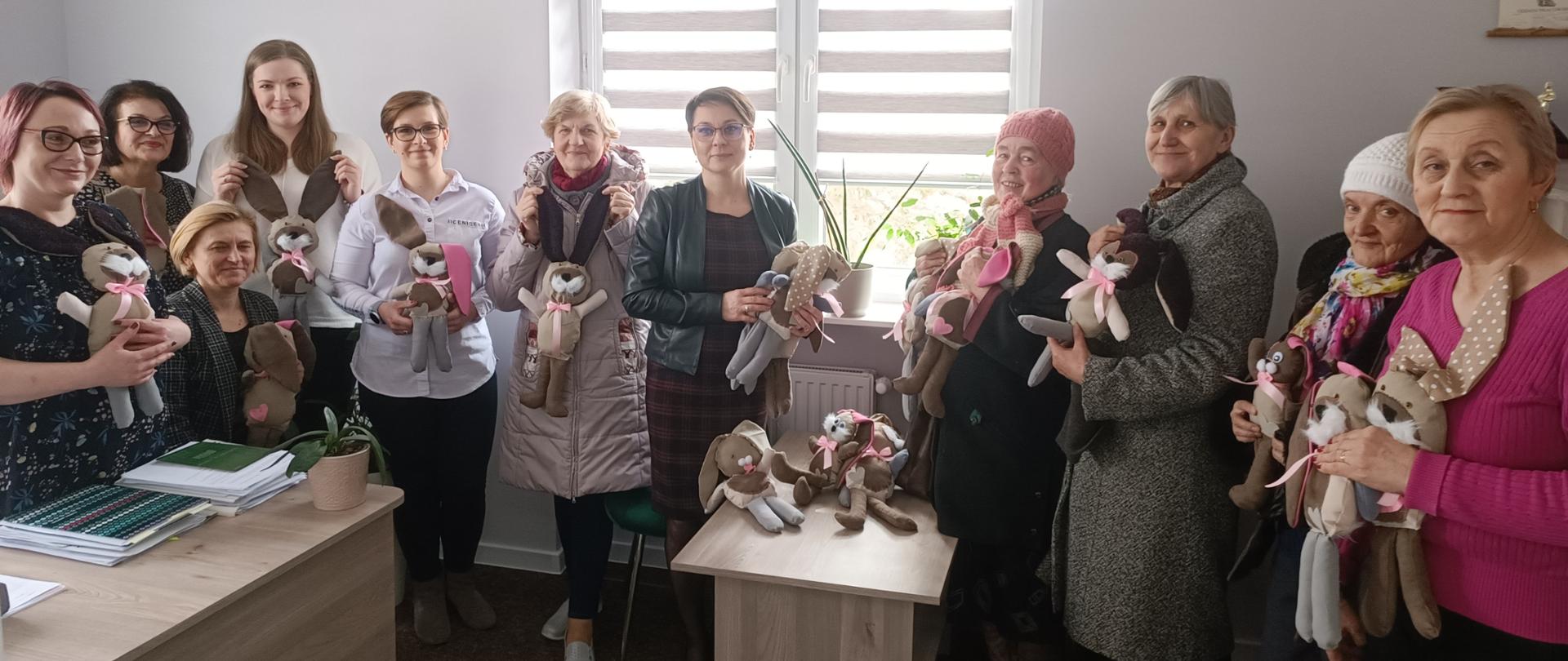 Członkowie Klubu Senior + i pracownicy MOPS w Dąbrowie Białostockiej pozujący do zdjęcia z wykonanymi maskotkami.
