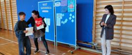 Uczeń odbiera dyplom w konkursie na najlepszy plakat przeciw przemocy od pani pedagog i pani wicedyrektor