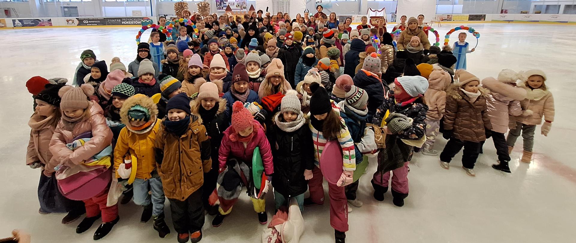 Zdjęcie grupowe dzieci na tafli lodowiska z aktorami z przedstawienia.