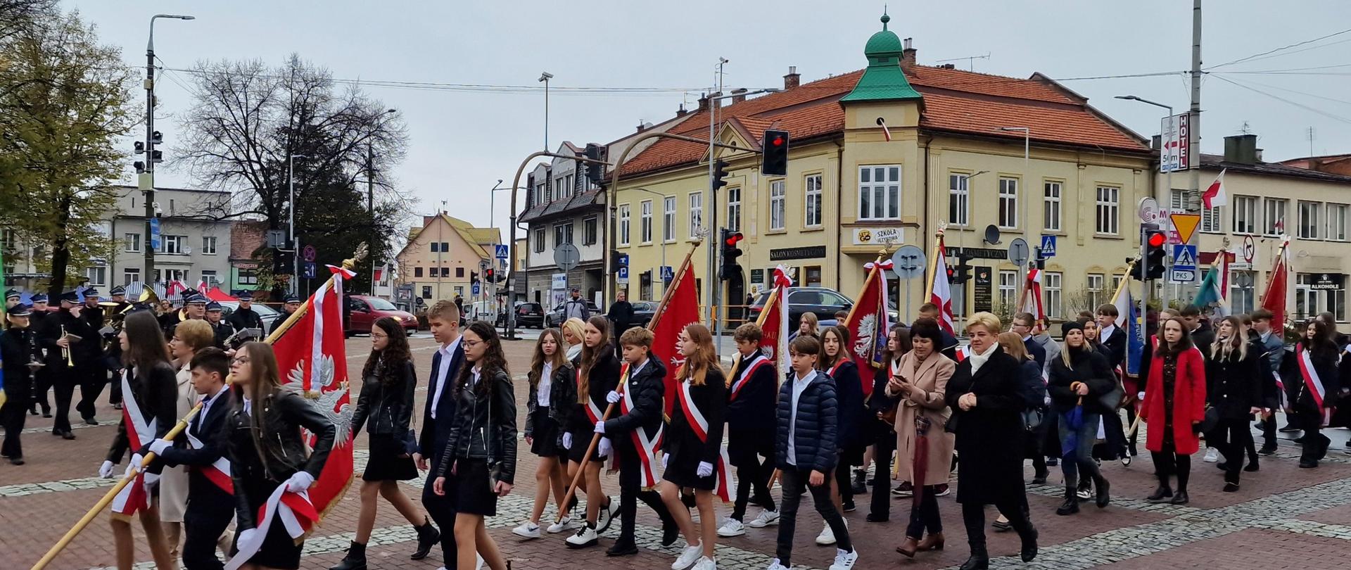 Grupa ludzi w której na czele znajdują się dyrektorzy i uczniowie szkół oraz przedstawiciele organizacji działających na terenie Gminy Kalwaria Zebrzydowska maszeruje do kościoła pw. Świętego Józefa w Kalwarii Zebrzydowskiej gdzie zostanie odprawiona msza święta za Ojczyznę.