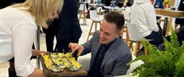 Basia Budnik - pracownik Starostwa Powiatowego, częstuje regionalnymi przysmakami uczestnika targów 