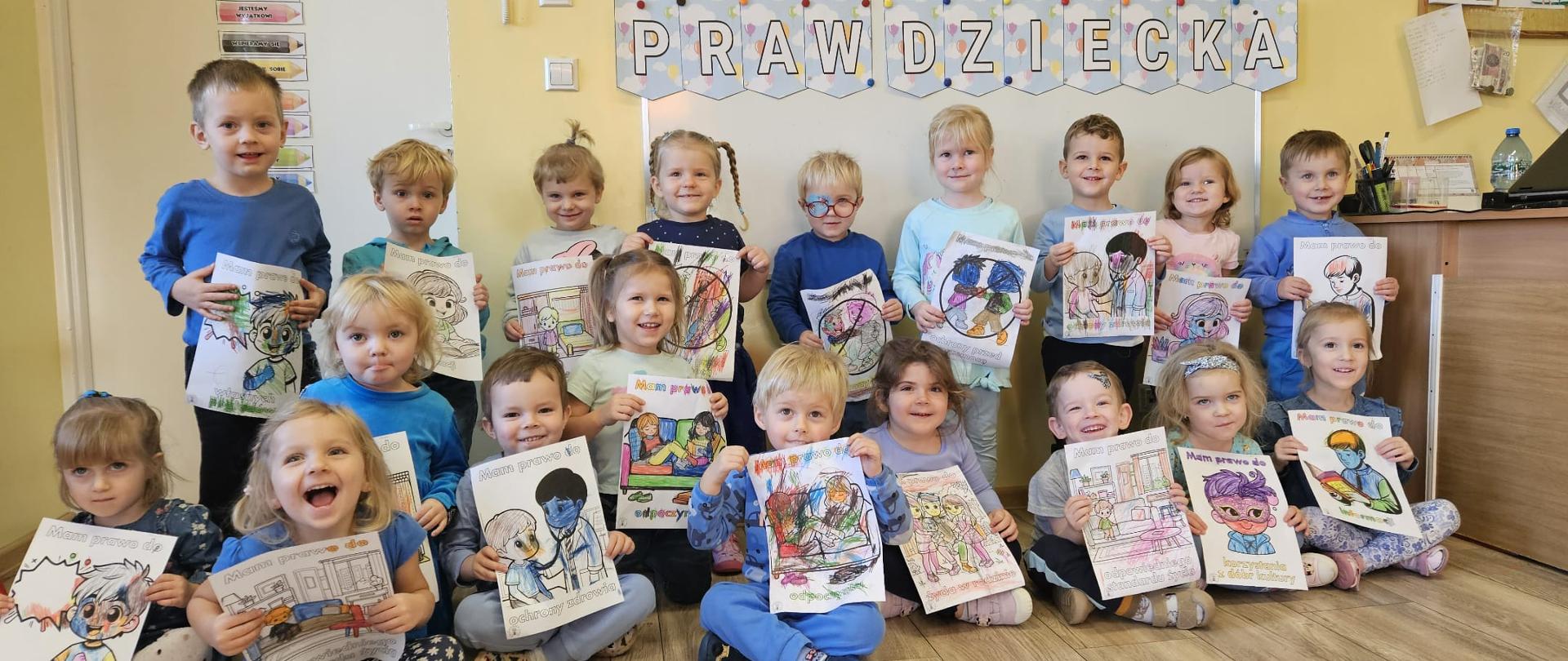 Grupa dzieci prezentuje kolorowanki z okazji Dnia Praw Dziecka 