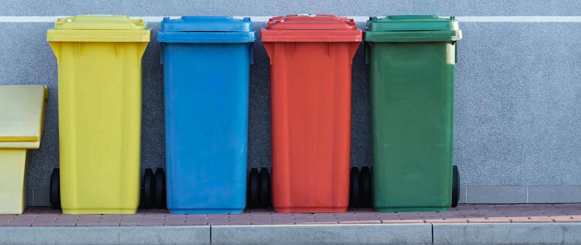 Na zdjęciu widoczne są 4 kosze na śmieci. Od lewej żółty, niebieski, czerwony i zielony. 