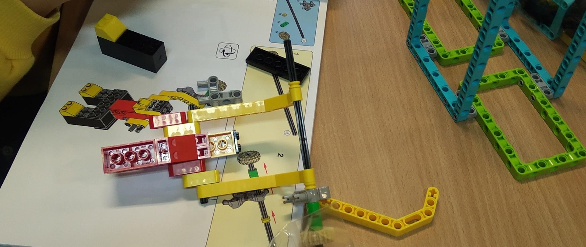 Rozłożona na stole instrukcja, na niej kolorowe klocki lego