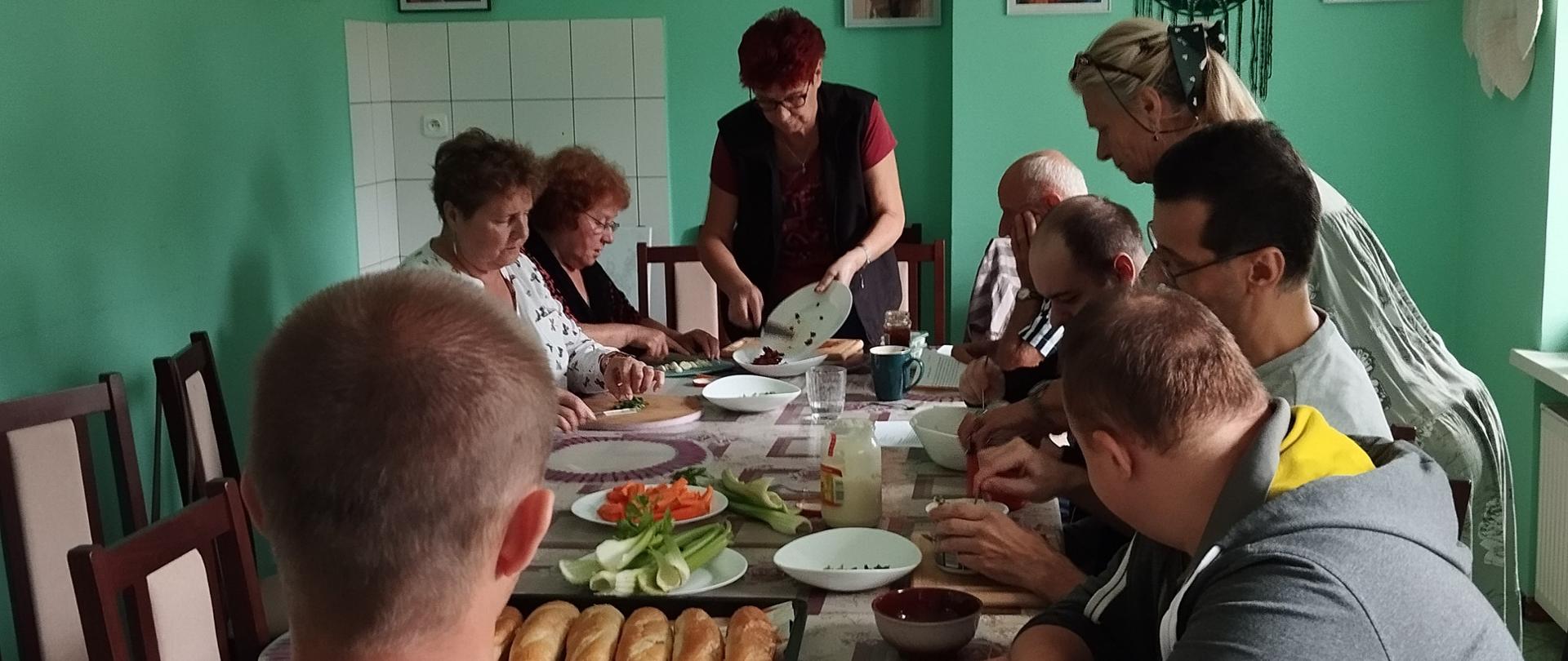 członkowie klubu senior+ wraz z uczestnikami warsztatów terapii zajęciowej przygotowujący potrawy