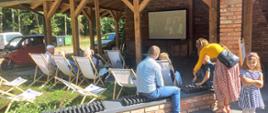 Osoby leżą na leżakach, oglądają film