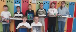 Uczniowie trzymają w ręku makiety fantastycznego świata z lektury pt. "Opowieści z Narnii. Lew, Czarownica I stara szafa"