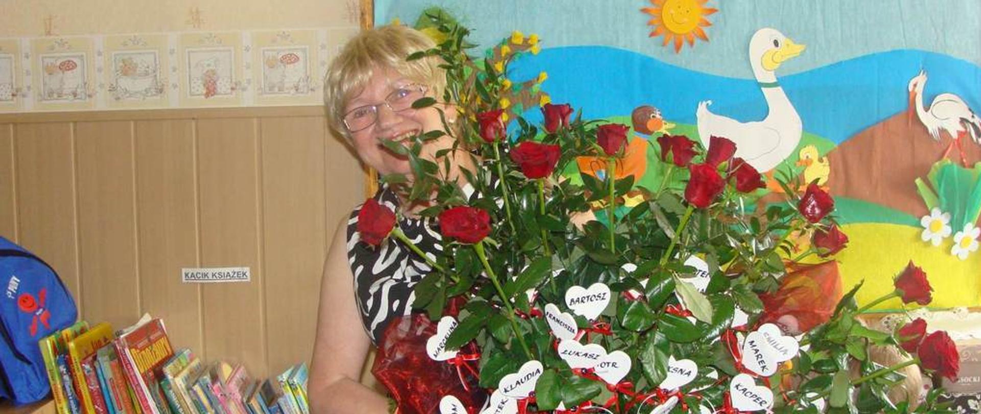 Uśmiechnięta kobieta, która trzyma w dłoniach duży bukiet róż. 