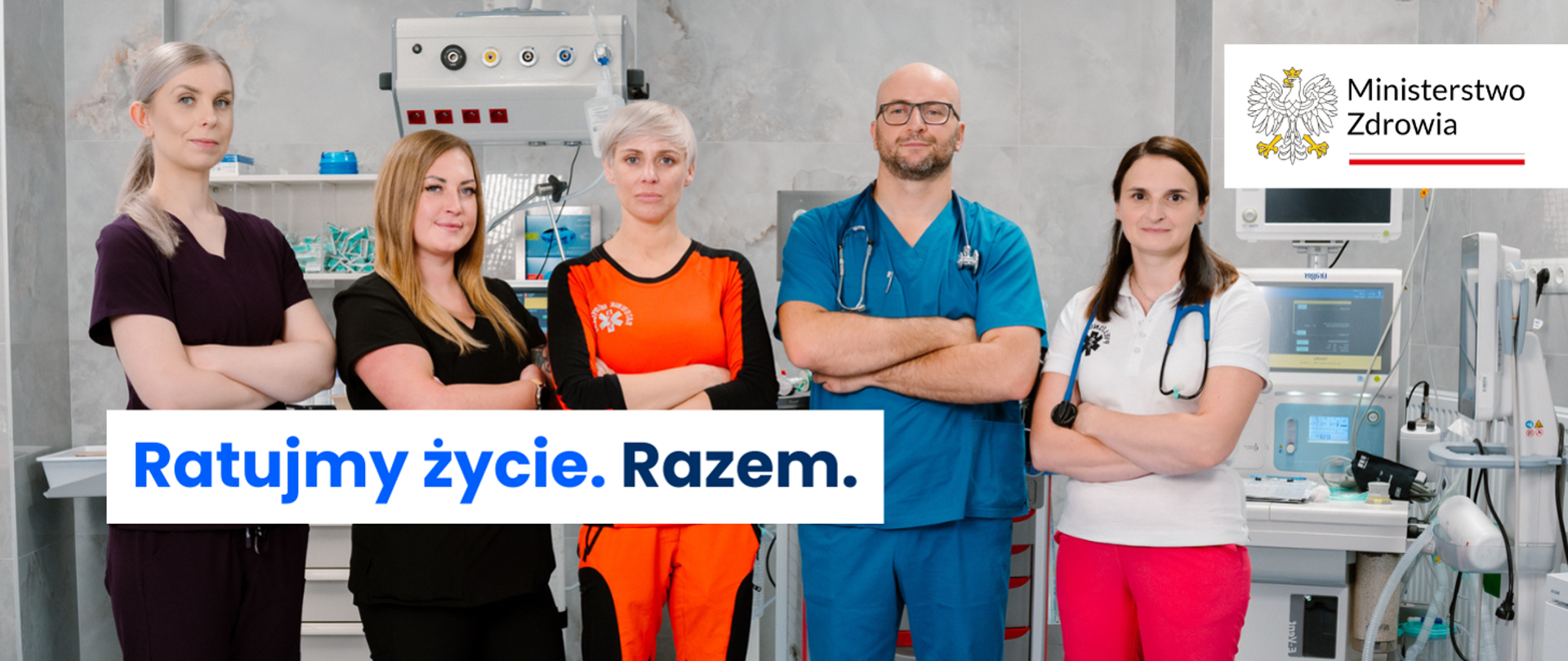 Grupa pracowników medycznych w szpitalu, obok napis: Ratujmy życie. Razem. i logo Ministerstwa Zdrowia.