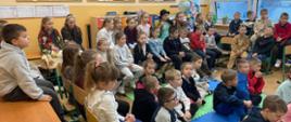Uczniowie klas I-III siedzą na krzesłach w klasie, część w roli widzów i słuchaczy, część w odświętnych ubraniach oczekuje na swój występ w konkursie